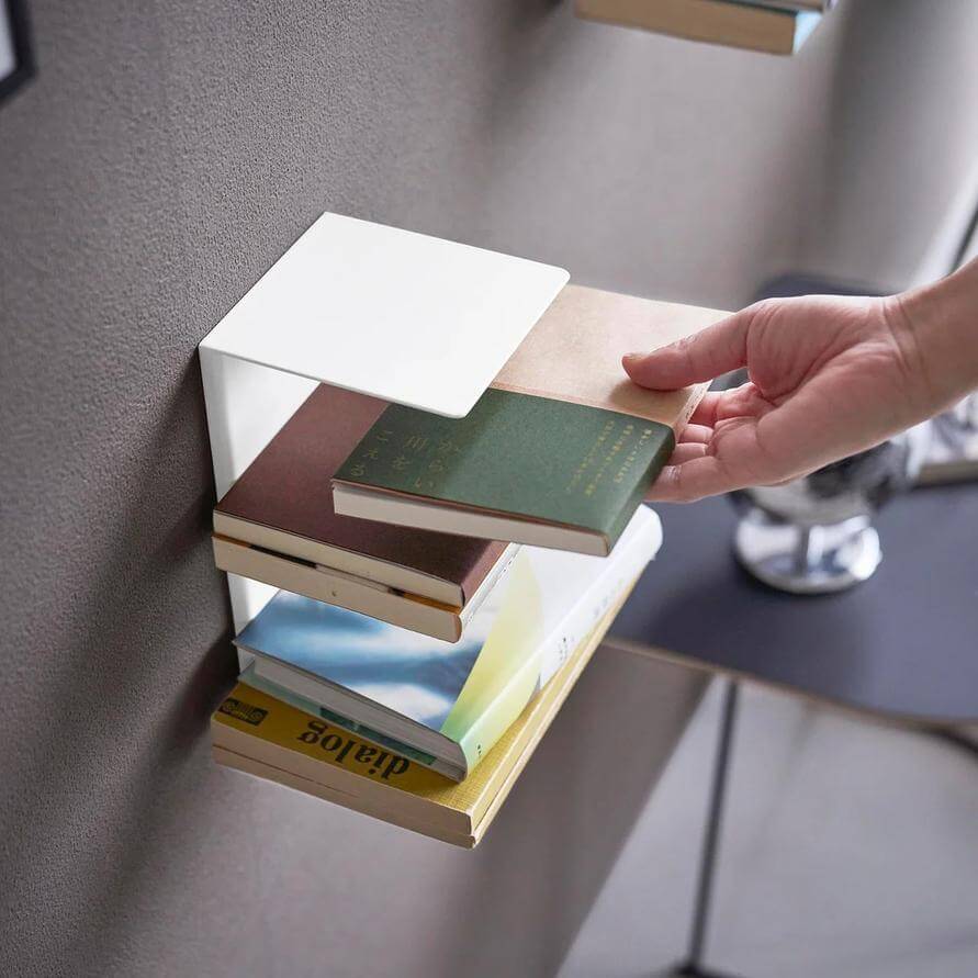 手從壁掛書架的平放書堆抽出一本書