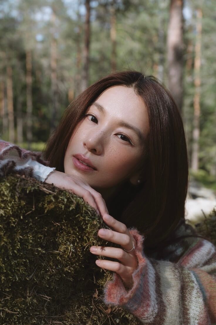 田馥甄在森林裡倚靠覆有青苔的岩石,望向鏡頭