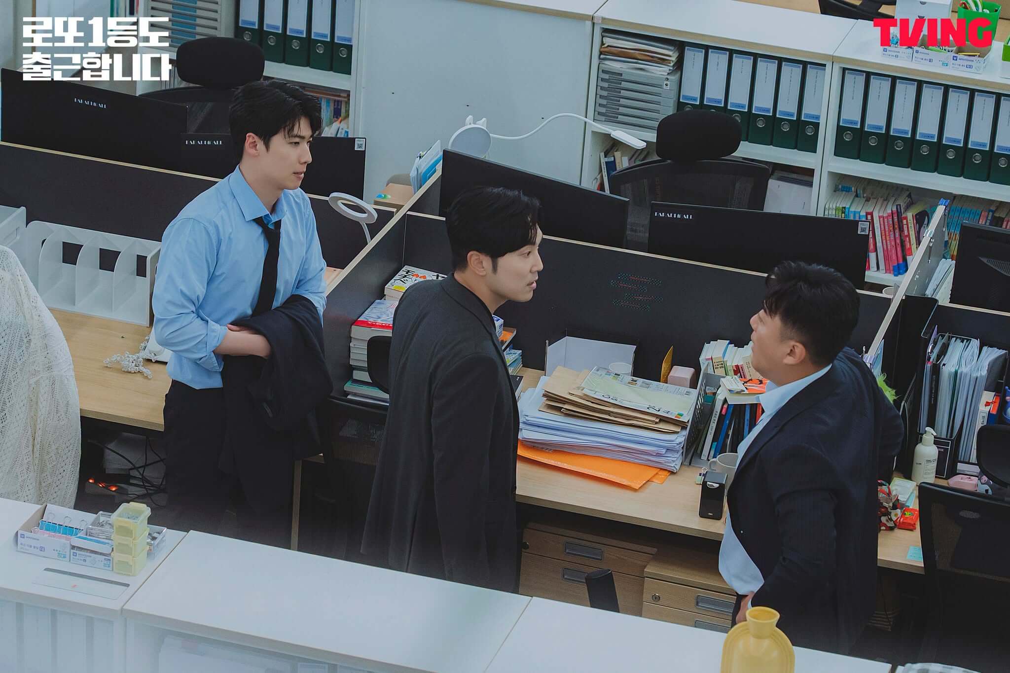 《中頭獎還是要上班》三位角色在擺滿文件的辦公桌旁交談