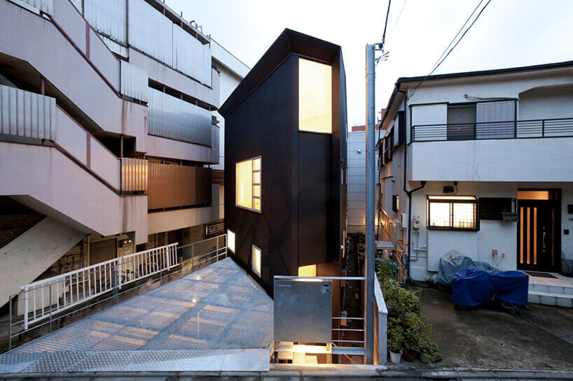 東京OH House深色住宅前方設有鋼網停車平台,右側階梯往下通往入口